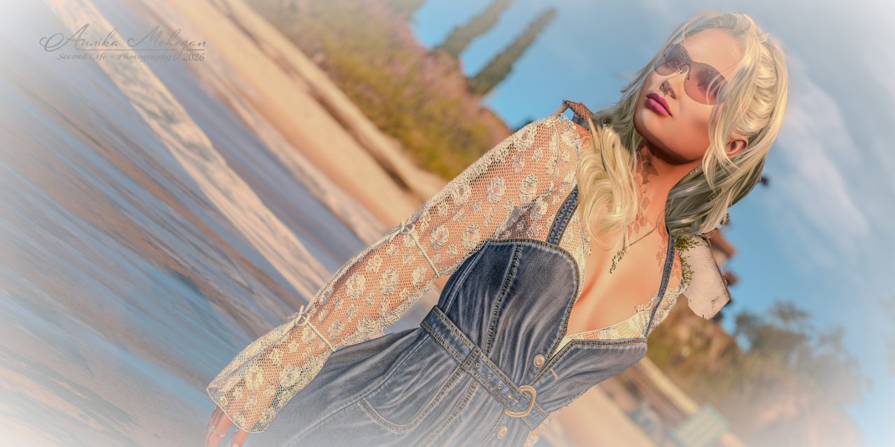 Annika im Gegenlicht am Strand: kurzes Denim-Trägerkleid von adorsy über einem cremefarbenen Spitzentop mit weiten Ärmeln